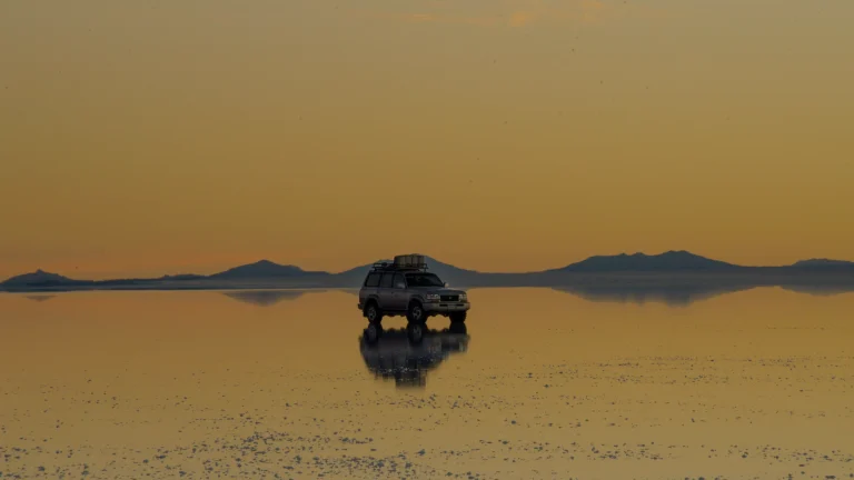 Un 4x4 sur la surface réfléchissante du Salar d'Uyuni au coucher du soleil